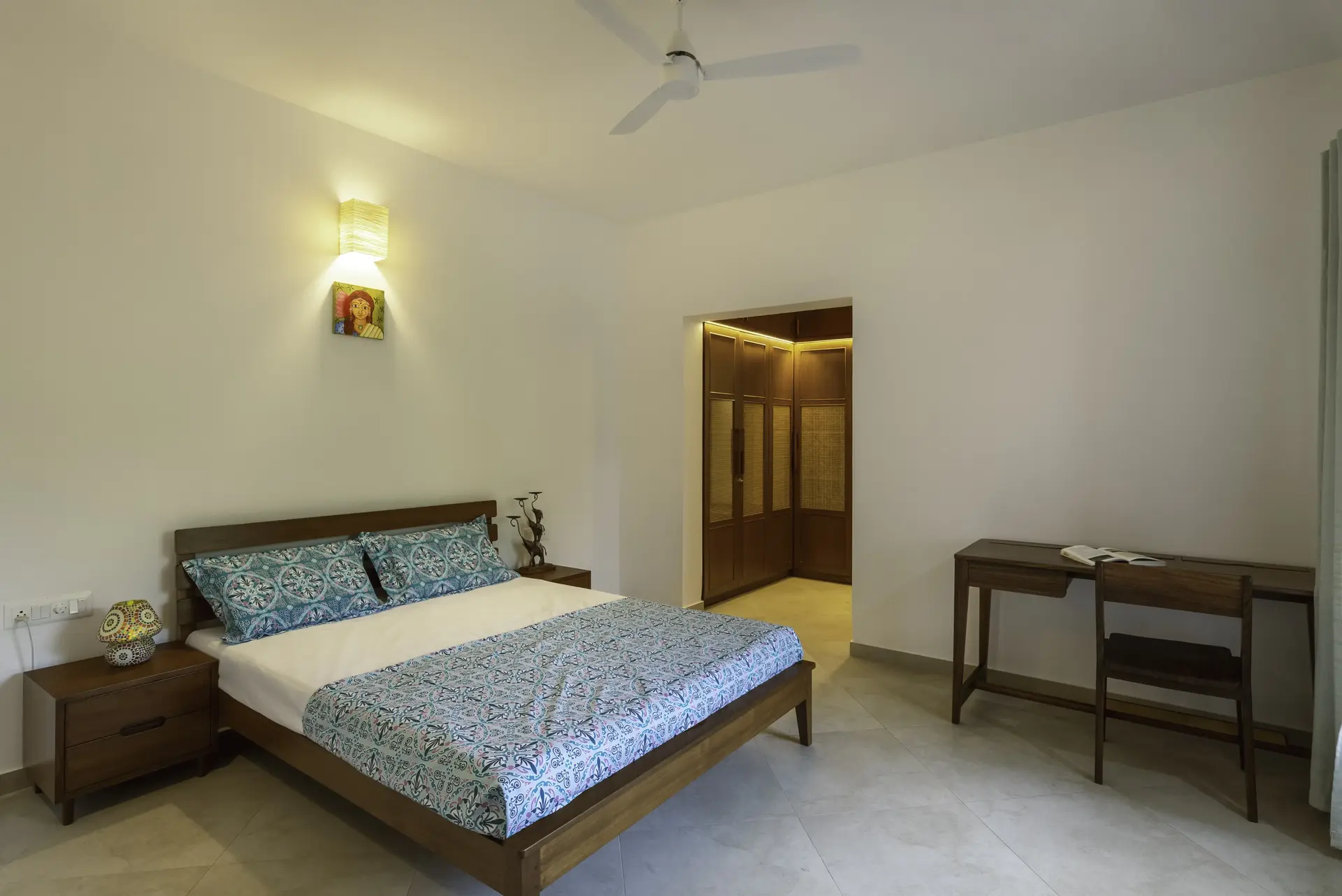 Queen bed with slats for backrest and light blue bed sheets with a side table